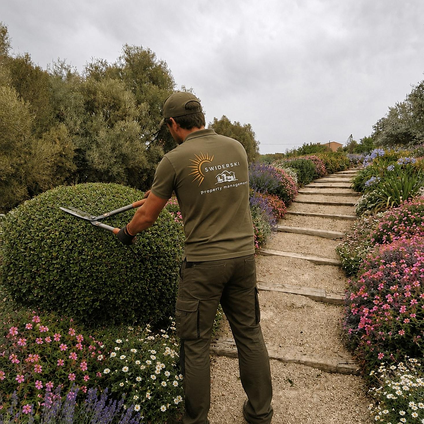 Mitarbeiter beim Heckenschnitt an einem bepflanzten Gartenweg